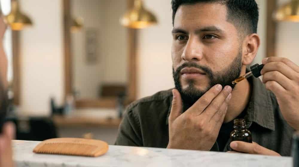 Hombre aplicando aceite a su barba como rutina de cuidado